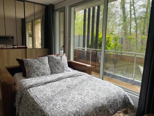 a bedroom with a bed and a large window at Havre de paix avec jardin et parking à Chantilly in Gouvieux