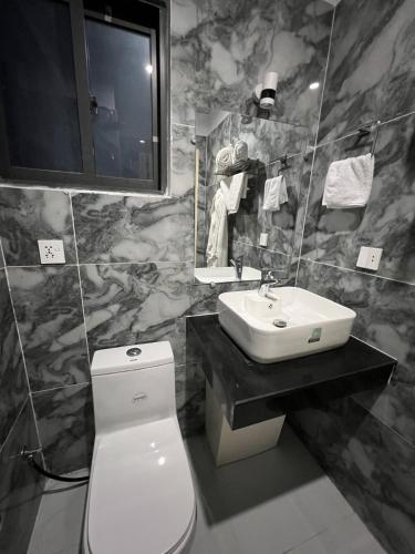 a bathroom with a white toilet and a sink at Courteous Hotel in Islamabad