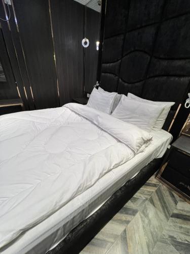 a white bed with a black headboard and white pillows at Courteous Hotel in Islamabad