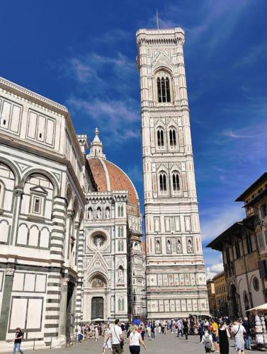 a large building with a tall tower with people walking around it at PassionToscane in San Giovanni dʼAsso