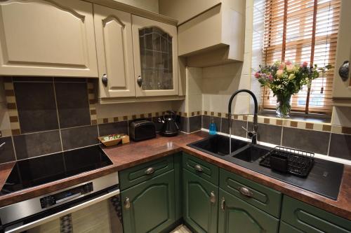 a kitchen with green cabinets and a sink at Samuels' a duplex apartment by Spires Accommodation in Lichfield City Centre in Lichfield