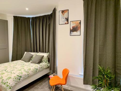 a bedroom with a bed and a chair and a window at Beautiful Double Ensuite Room in Erith