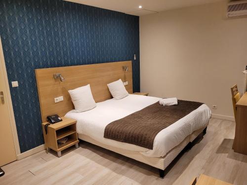 une chambre avec un grand lit avec une tête de lit en bois dans l'établissement Hôtel de L'Ecu, à Montbard