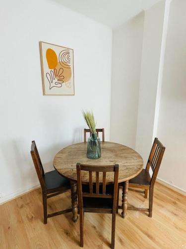 une table de salle à manger avec des chaises et un vase dessus dans l'établissement T2 Cosy & Elegant en Plein Coeur de Carcassonne, à Carcassonne