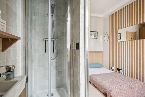 une petite salle de bain avec douche et un lit dans l'établissement Charming studio - 1P - Porte-Dauphine-Trocadero, à Paris