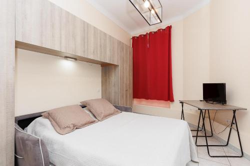 une chambre avec un lit blanc et un rideau rouge dans l'établissement Carrousel stud, à Cannes