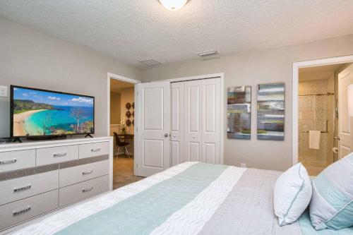 a bedroom with a bed and a flat screen tv at Beautiful 4BD home Themed Pool and Grill 4417 in Kissimmee