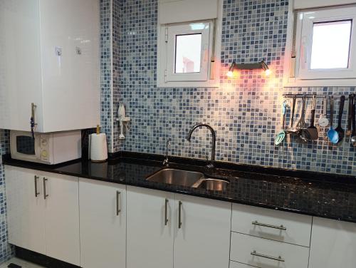 a kitchen with a sink and a tile wall at Apartamento Mare Nostrum in Puerto de Mazarrón