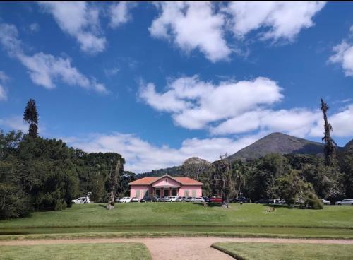 a pink building in a field with mountains in the background at Apartamento completo no Centro de Nova Friburgo in Nova Friburgo