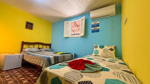 two beds in a room with yellow and blue walls at Casa Bantu - Vila Rosa in Vera Cruz de Itaparica