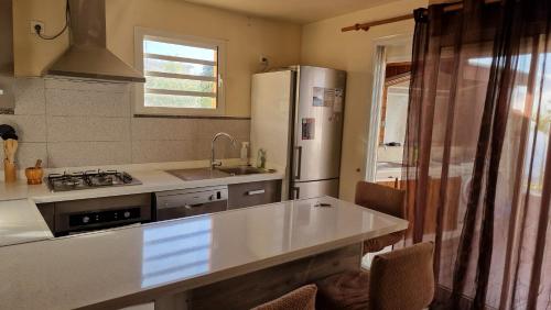 a kitchen with a white refrigerator and a sink at Vacances paisibles - petit déjeuner offert pour la première nuit in Saint-Paul