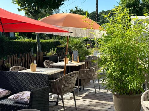 d'une terrasse avec des tables et des chaises et un parasol. dans l'établissement Hôtel Le Boïate, à Arès