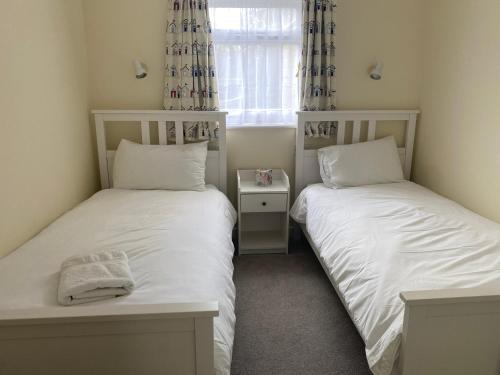 two twin beds in a room with a window at The Cottage, ground floor property near the beach in Seaview