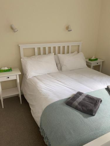 a bedroom with a white bed and two tables at The Cottage, ground floor property near the beach in Seaview