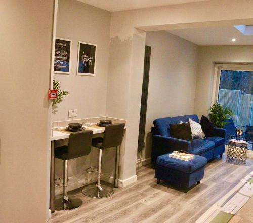 a living room with a table and a blue couch at Beautiful Double Ensuite Room in Erith