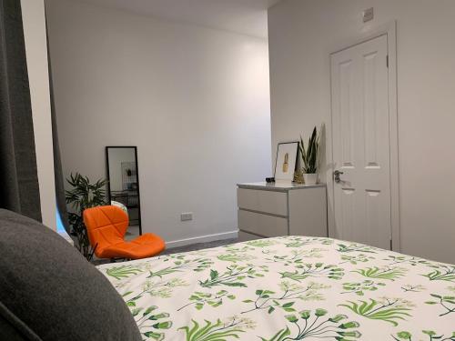 a bedroom with a bed and an orange chair at Beautiful Double Ensuite Room in Erith