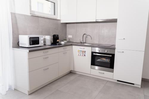 a kitchen with white cabinets and a microwave at GrenzApartments in Bietingen
