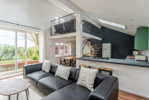 a living room with a black couch and a kitchen at Luxury self contained one bedroom - Sawbridgeworth in Sheering
