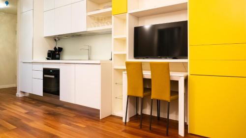 a kitchen with a desk with two chairs and a tv at Luxury Flat - WiFi, AC, Walk to Brera & Duomo in Milan