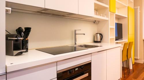 a kitchen with white cabinets and a sink at Luxury Flat - WiFi, AC, Walk to Brera & Duomo in Milan