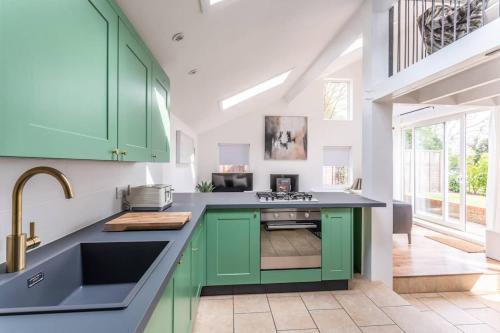 a kitchen with green cabinets and a sink at Luxury self contained one bedroom - Sawbridgeworth in Sheering
