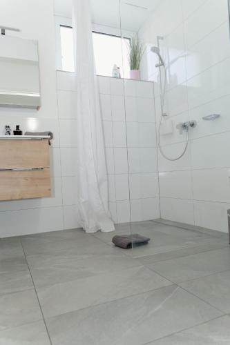 a bathroom with a shower and a tile floor at GrenzApartments in Bietingen