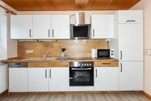 a kitchen with white cabinets and a microwave at Flut in Esens