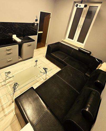 a living room with a black couch and a kitchen at Dark Romance- Apartament BDSM Greya dla Zakochanych Par in Ruda Śląska