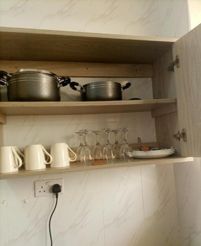 a shelf with pots and pans and wine glasses at Homes by lucy in Mombasa