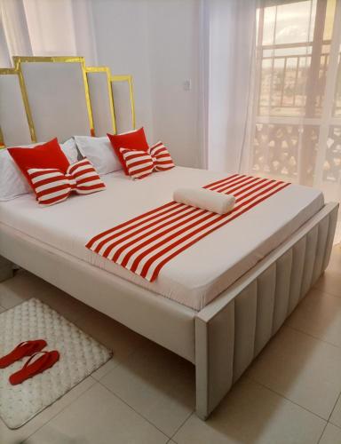 a large bed with red and white striped pillows at Homes by lucy in Mombasa