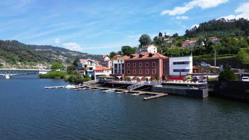 a town on the river with boats in the water at Douro Hotel Porto Antigo in Cinfães
