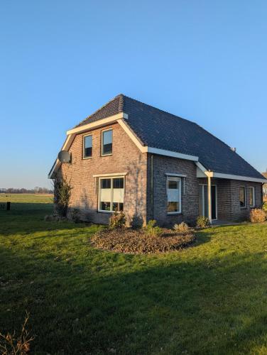 a brick house in a field with a large yard at Vrijstaande Landelijke Woning in Slagharen