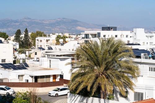 a city with white buildings and a palm tree at Mountain View Suite in Ayios Dhometios