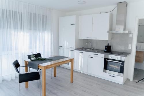 a kitchen with white cabinets and a wooden table at GrenzApartments in Bietingen