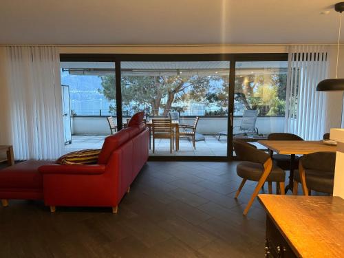a living room with a red couch and a table at Appartamento fronte lago in Muralto