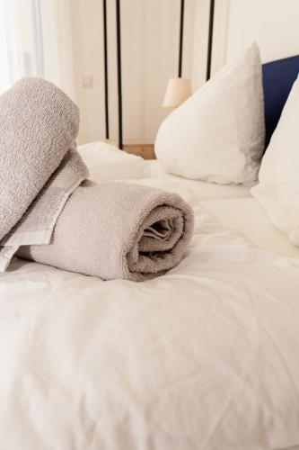 a towel is laying on a white bed at GrenzApartments in Bietingen