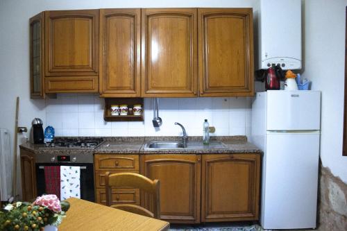 a kitchen with wooden cabinets and a sink and a refrigerator at Casa ARGENTINA in Spoleto