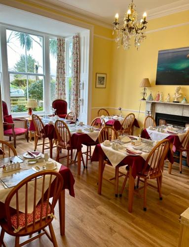 a dining room with tables and chairs and a fireplace at Rosalie Guest House in Penzance
