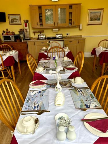 a dining room with a long table with red and white dishes at Rosalie Guest House in Penzance