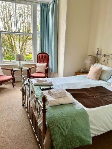 a bedroom with two beds and a chair and a window at Rosalie Guest House in Penzance