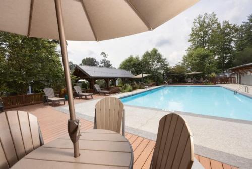 a swimming pool with chairs and an umbrella at Cozy 1BR Tiny Home with Pool Access and Free Tix in Flat Rock