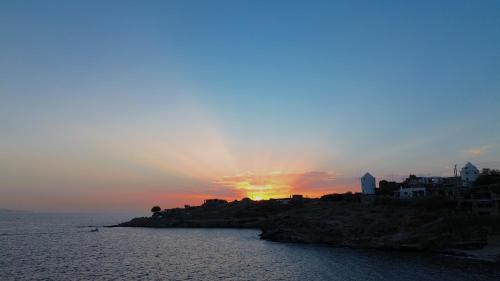 a sunset over a small island in the ocean at Kea Beachhouse in Koundouros
