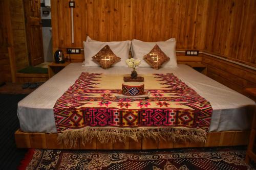 a bedroom with a large bed with a colorful blanket at Rustic wood house - A village home stay in Jibhi Valley in Jibhi