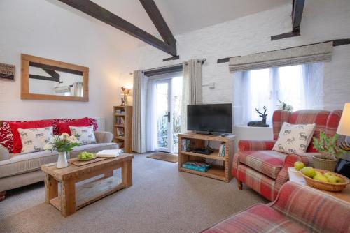 a living room with a couch and a tv at Rose Cottage in Paignton