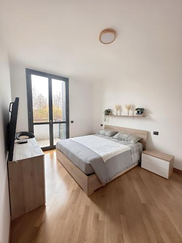 a white bedroom with a bed and a large window at Bed & Bergamo Casa Vacanze in Bergamo