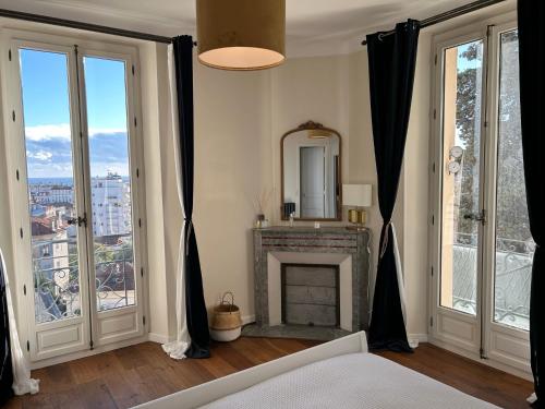 - une chambre avec une cheminée et de grandes fenêtres dans l'établissement Spacieux proche Palais Festival, à Cannes