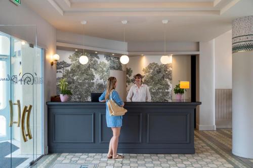 une femme debout à un comptoir dans un magasin dans l'établissement Hôtel Morgat Le Grand Hôtel De La Mer, à Crozon