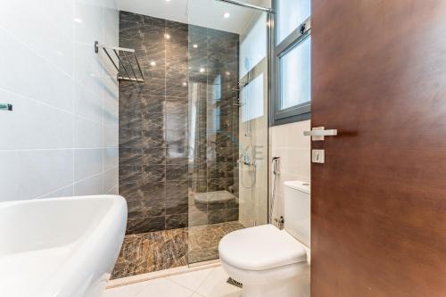 a bathroom with a toilet and a glass shower at Overlooking Pool & Sea Views Villa with BBQ Facility, Sharm - Al Dana Villa, Al Dana Island by Deluxe Holiday Homes in Fujairah