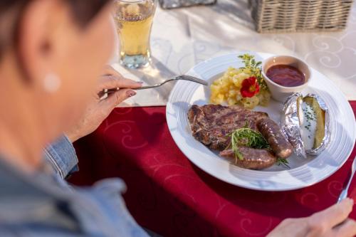 una donna seduta a un tavolo con un piatto di cibo di Der Oswalderhof a Obertilliach
