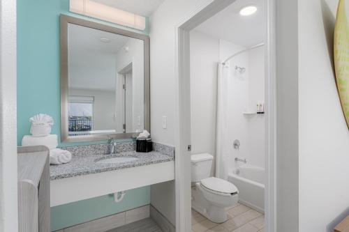 a bathroom with a sink and a toilet and a mirror at Surf & Sand Hotel in Pensacola Beach